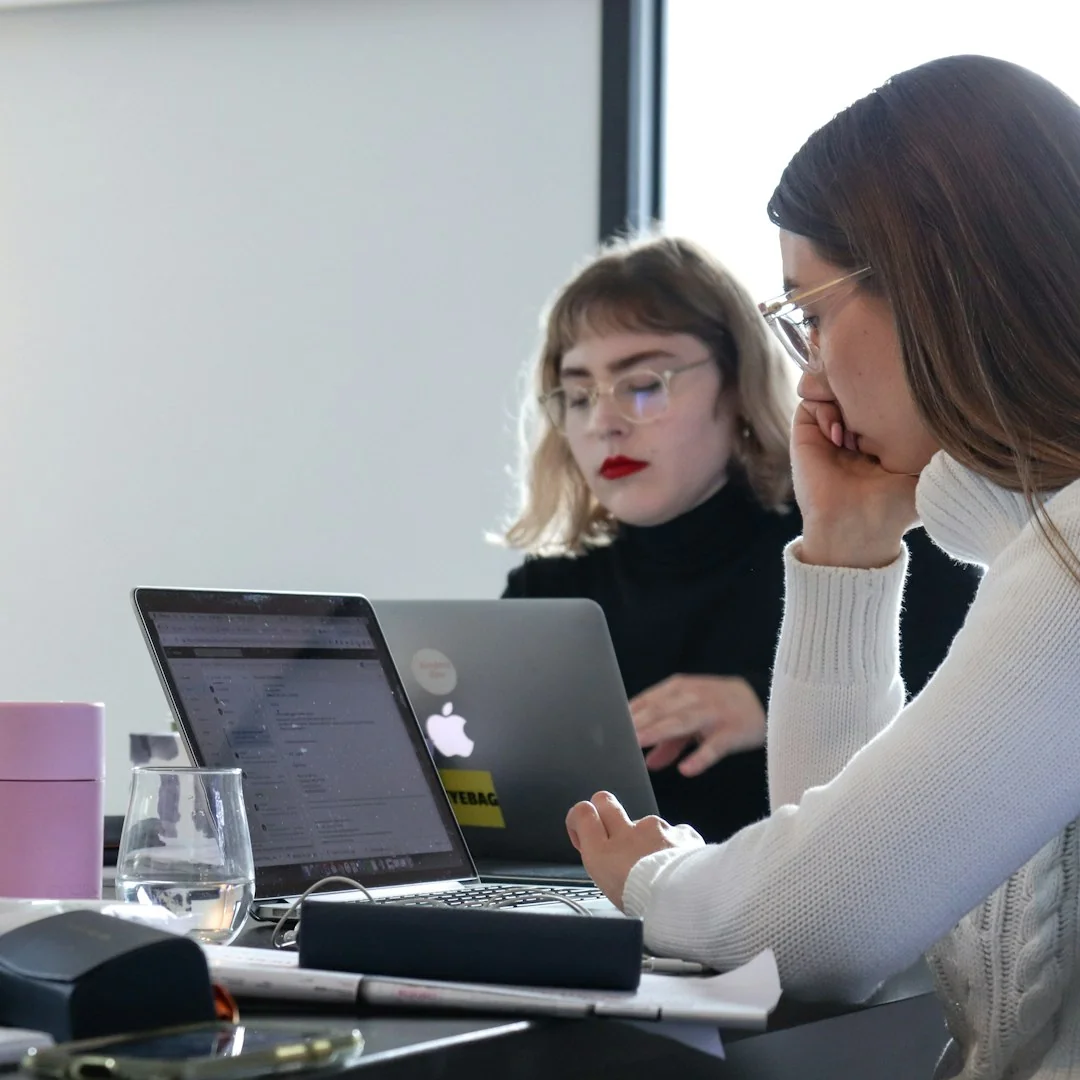 Person analyzes stock data with a smartphone and laptop, indoors.